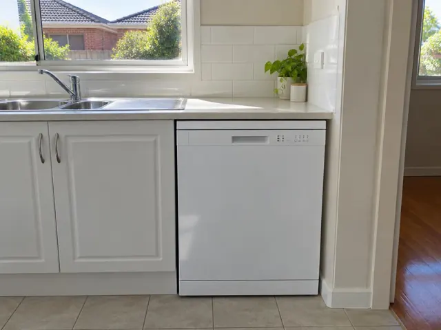 Built-in dishwasher beside a sink under a window in a white-tiled kitchen in Wallsend