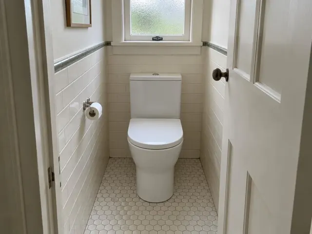 White toilet in a small tiled bathroom with frosted window and hex floor tiles in Jesmond